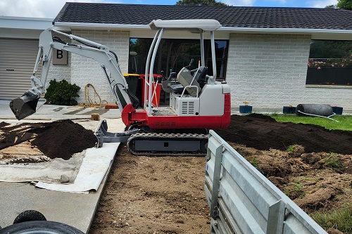 2t digger spreading earth with the driveway
                     protected by tarpaulins